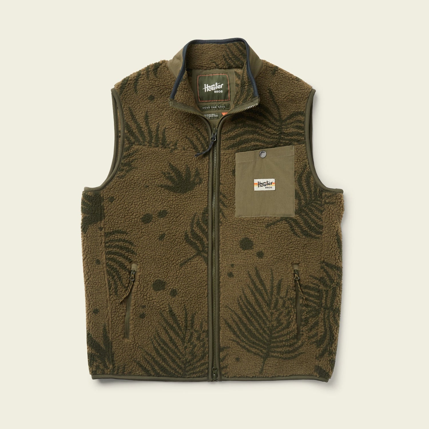 The Chisos Fleece Vest is a lightweight vest in olive green, crafted from high pile fleece. It features a zip front, fern leaf patterns, two zippered side pockets, and an olive chest pocket with a rectangular patch label.