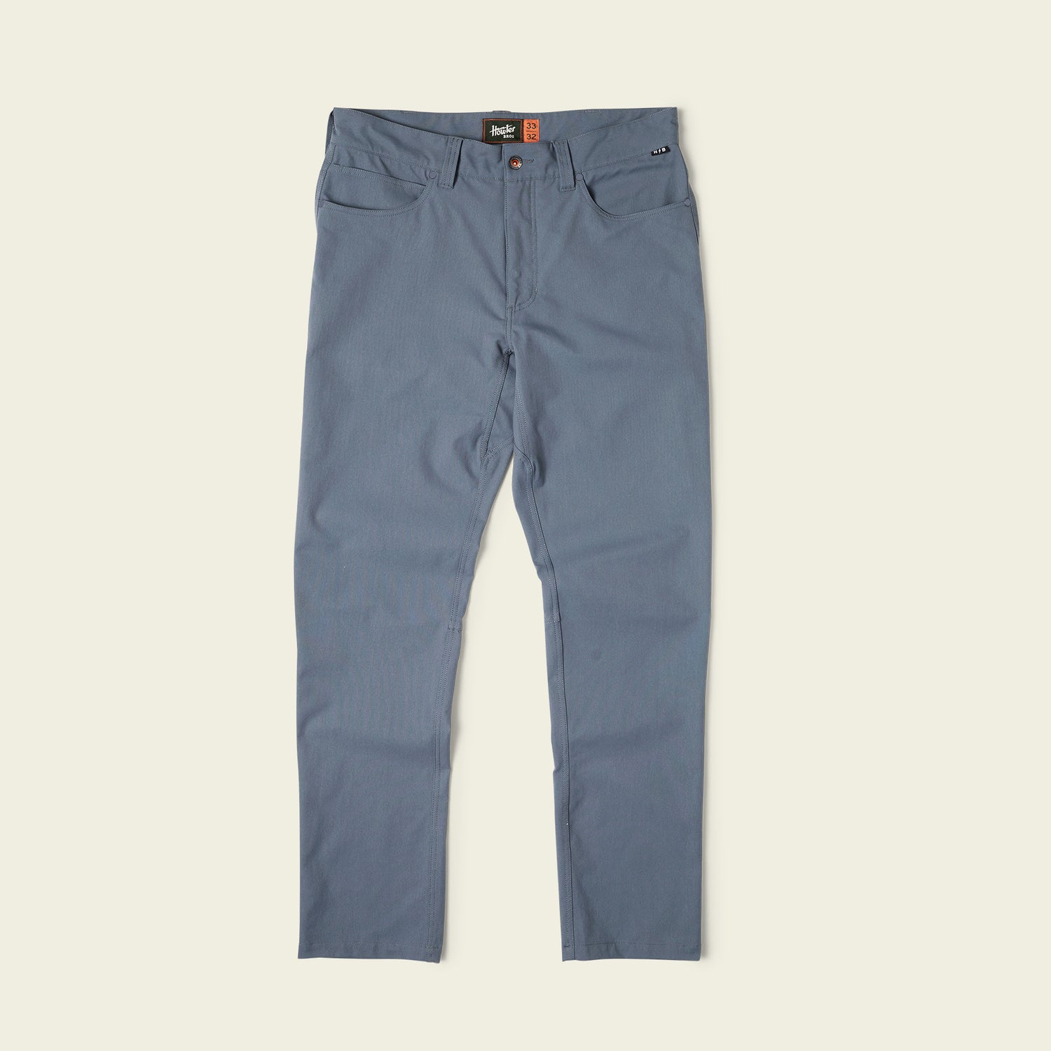A pair of blue Frontside Tech Pants with slim-fit design, front and back pockets, button and zipper closure, displayed flat on a light background.